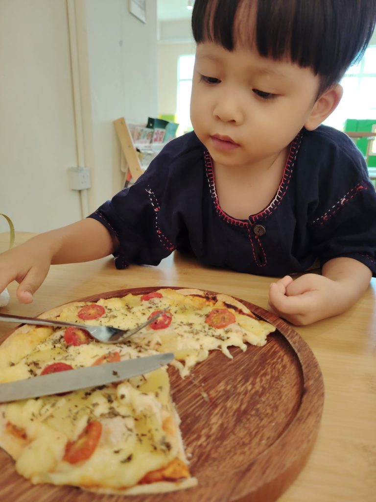 Child enjoying homemade pizza at Wulala Kidzland